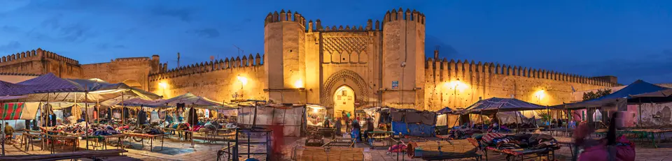 Market stalls below a floodlit gate at dusk