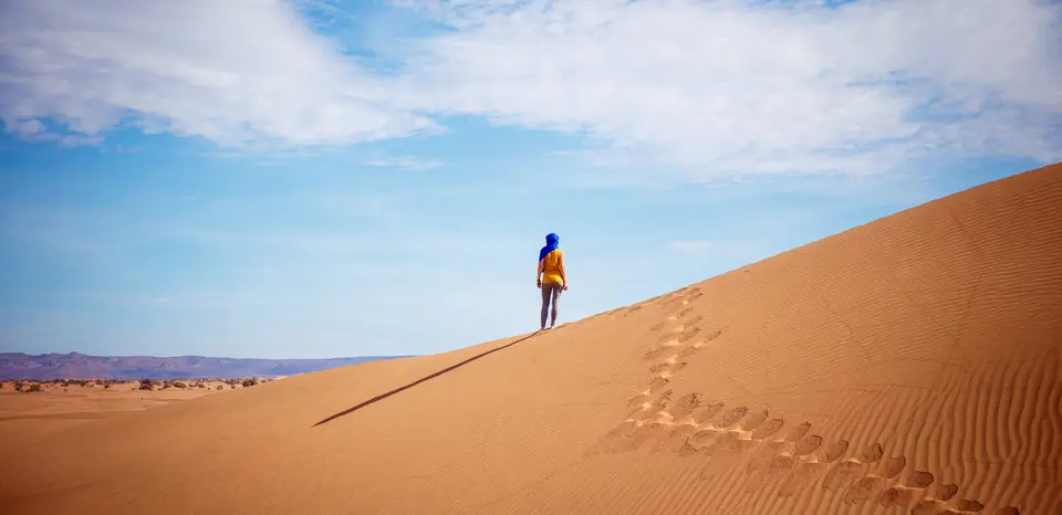 A traveler walking the crest of a dune