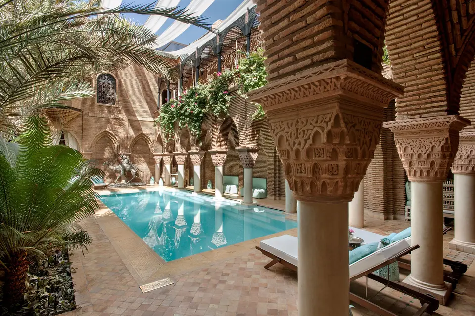 A riad courtyard with a pool and carved columns