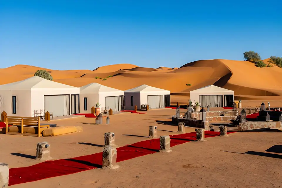 White tents of a desert camp among the dunes