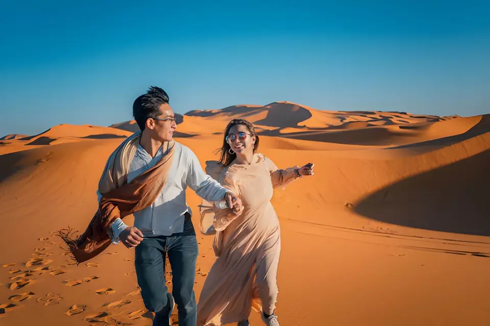A couple running down a dune
