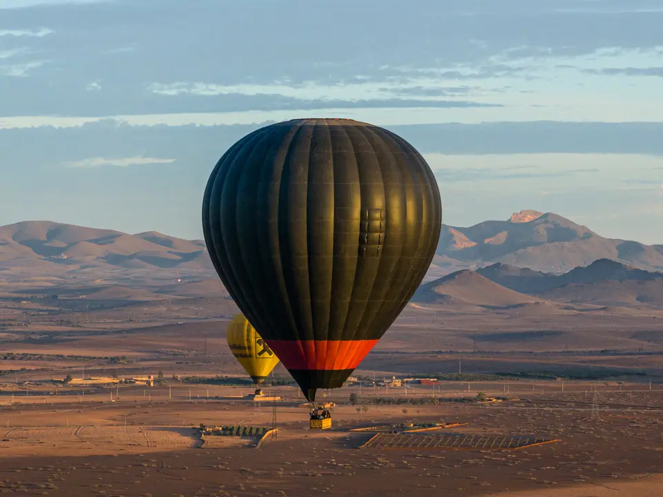 A hot air balloon low over the plain at sunrise