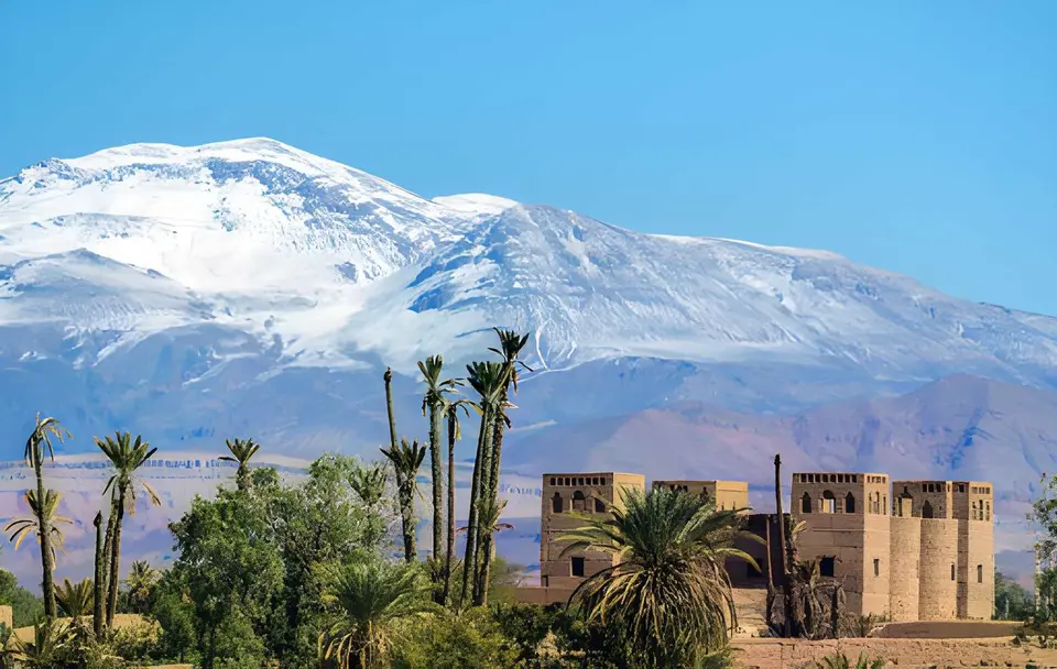 A kasbah and palms below the snow of the High Atlas