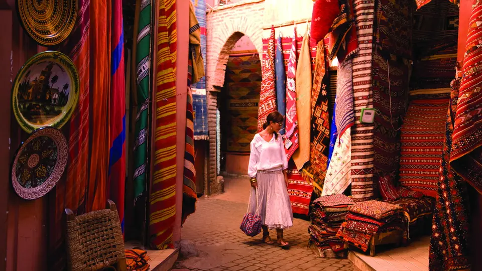 A traveler in a souk lane hung with rugs, Marrakech