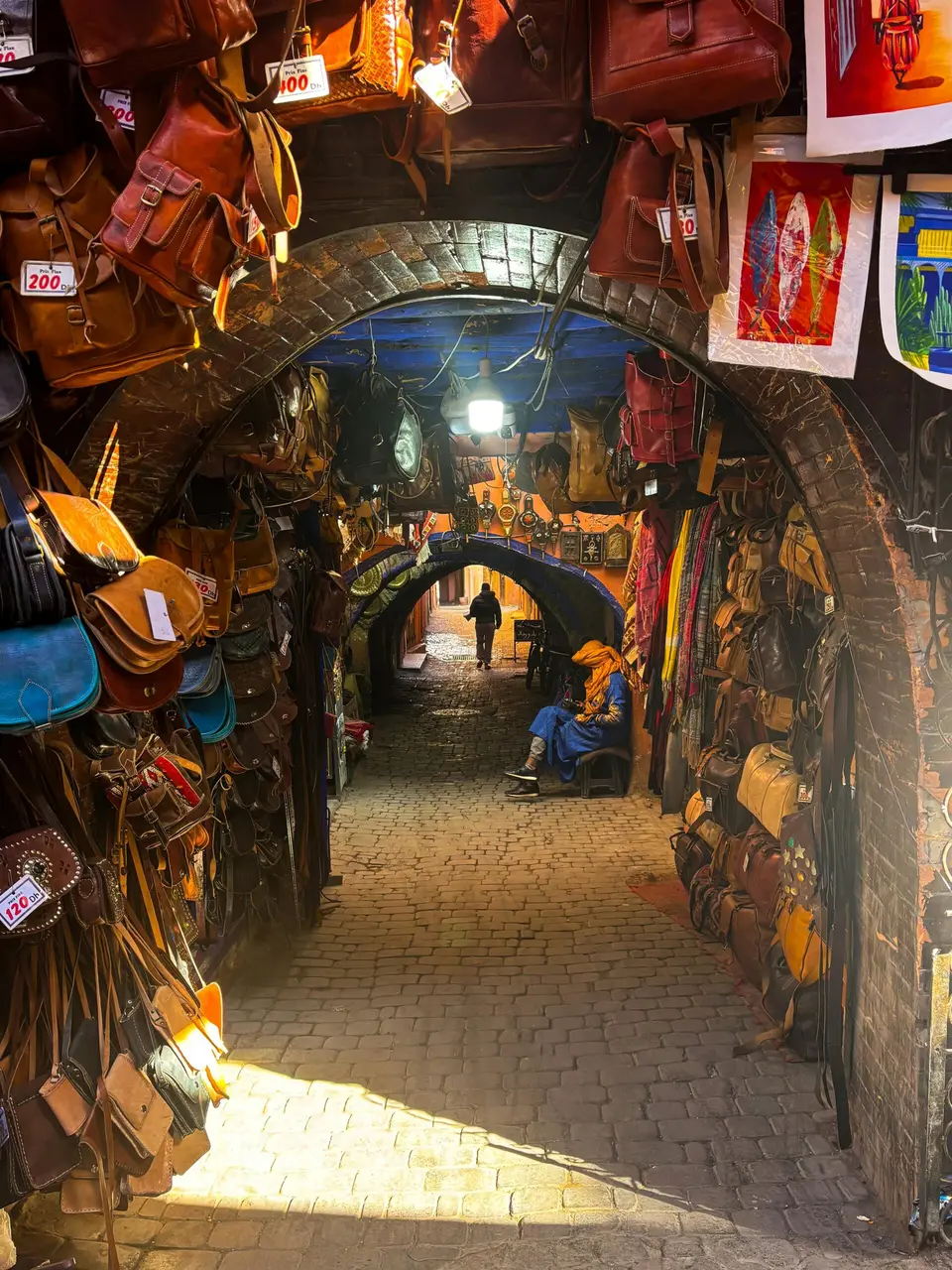 A covered souk lane hung with leather bags