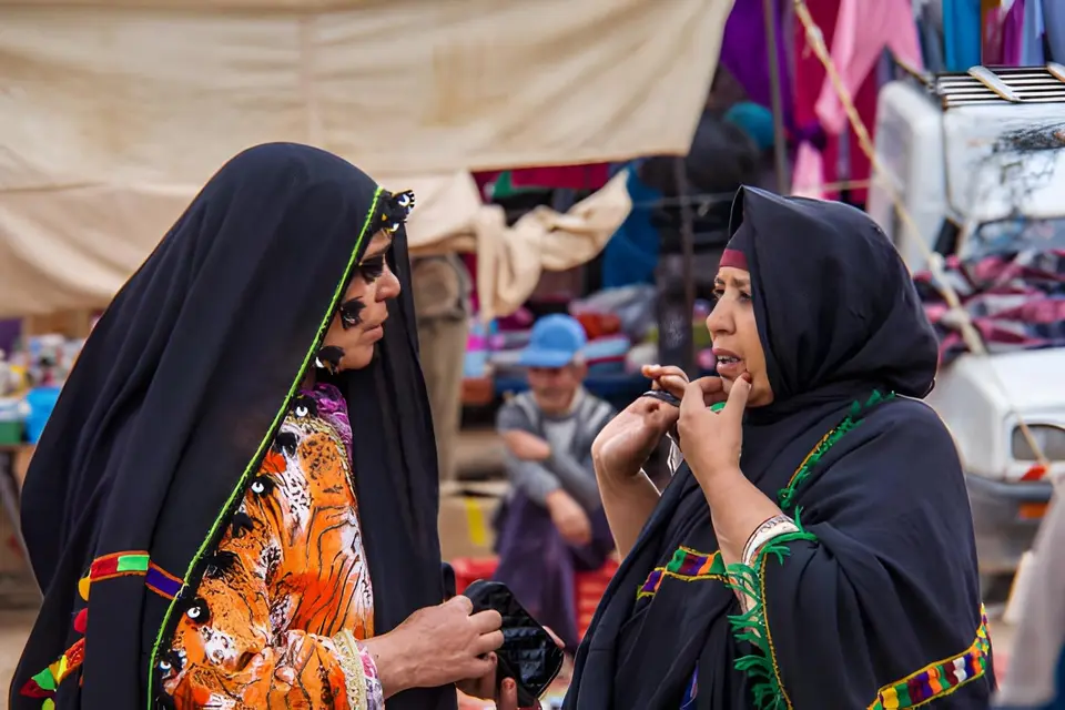 Two women in traditional haiks at a market