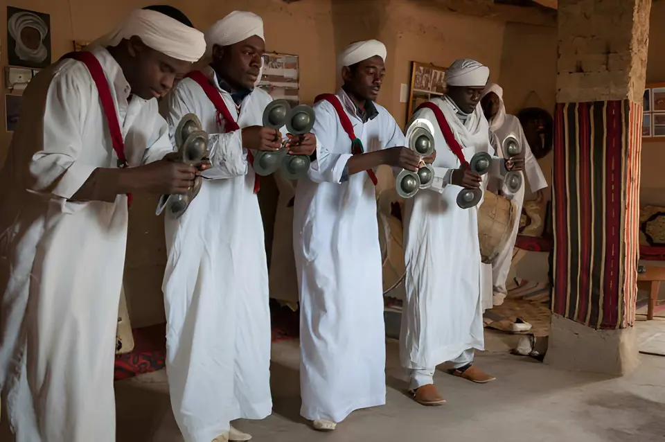 Gnaoua musicians in white robes playing qraqeb